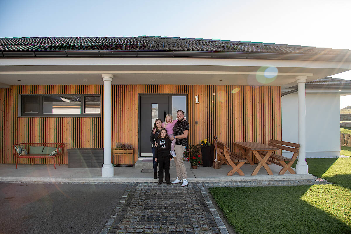 Familienfoto vor dem Hauseingang eines modernen Bungalows.