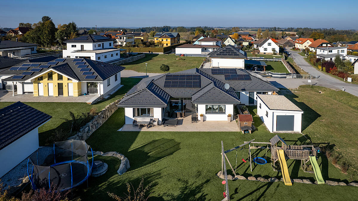 Rückansicht eines Bungalows mit Terrasse, Gartenmöbeln und Spielbereich.